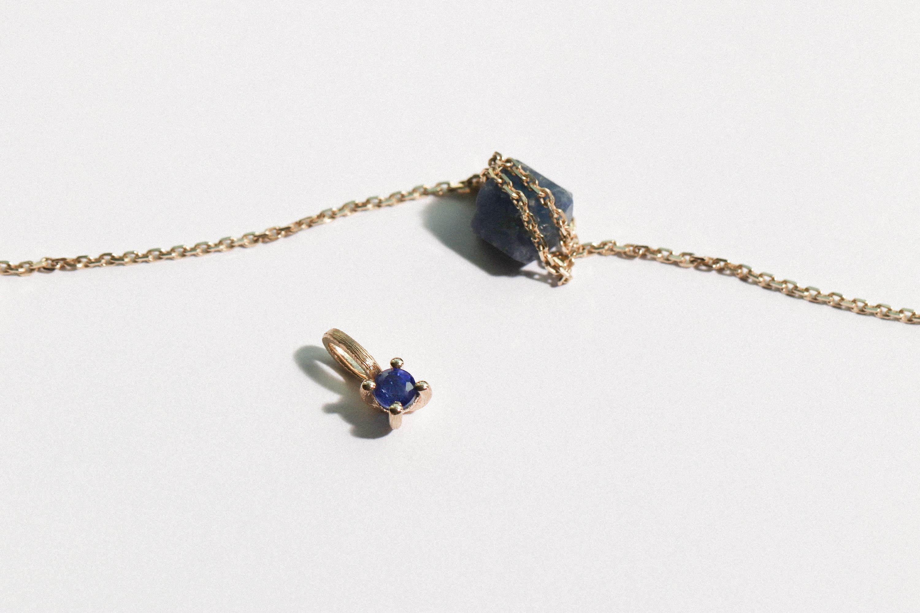 geboortesteen hanger met blauwe saffier, ketting over ruwe saffiersteen, ontdek betekenisvolle sieraden van narrae