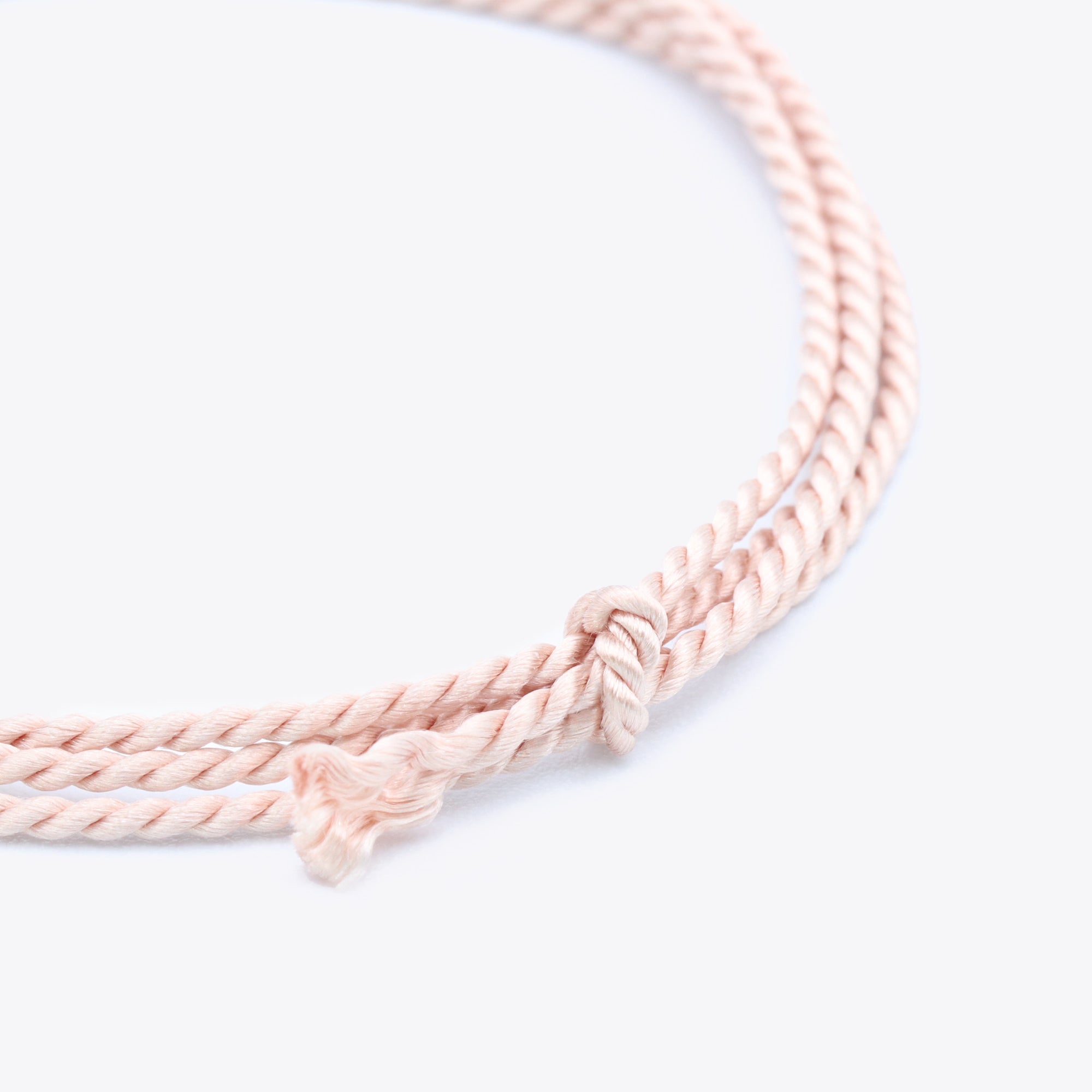Close-up van lichtroze natuursatijn koord voor het maken van een armband of ketting